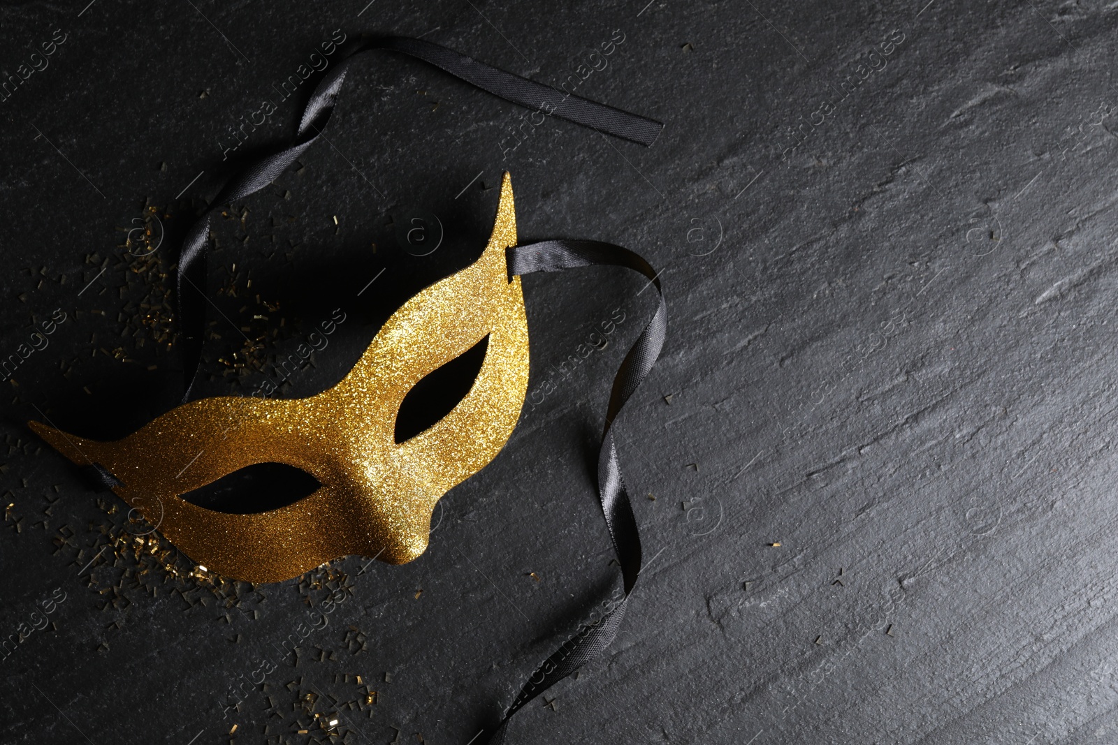 Photo of Beautiful golden carnival mask on grey textured table, top view. Space for text