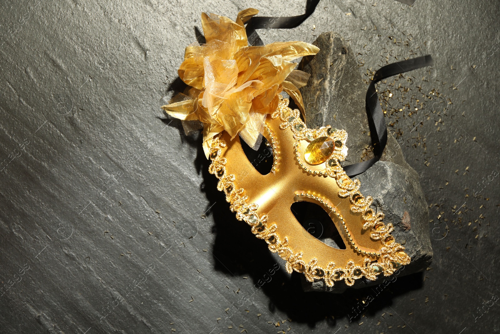 Photo of Beautiful golden carnival mask on grey textured table, top view