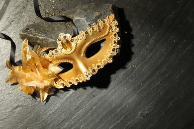 Photo of Beautiful golden carnival mask on grey textured table, top view. Space for text