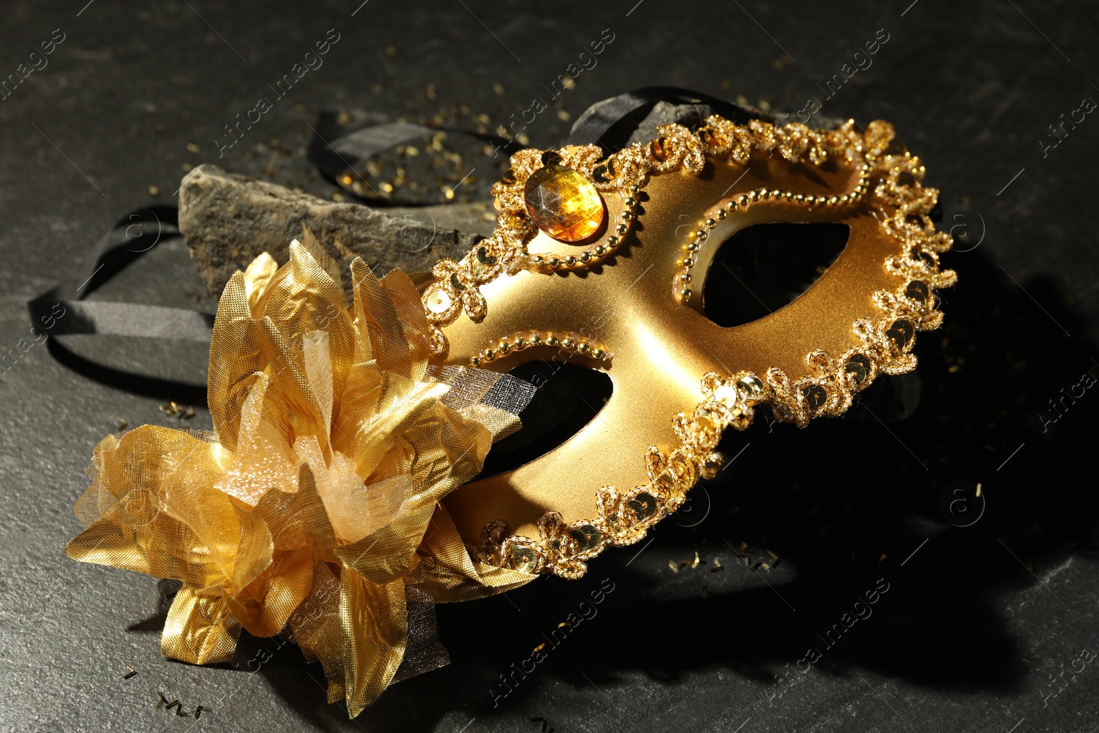 Photo of Beautiful golden carnival mask on grey textured table