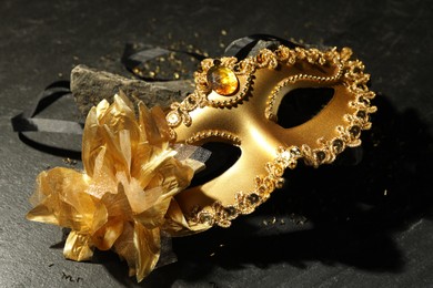 Photo of Beautiful golden carnival mask on grey textured table