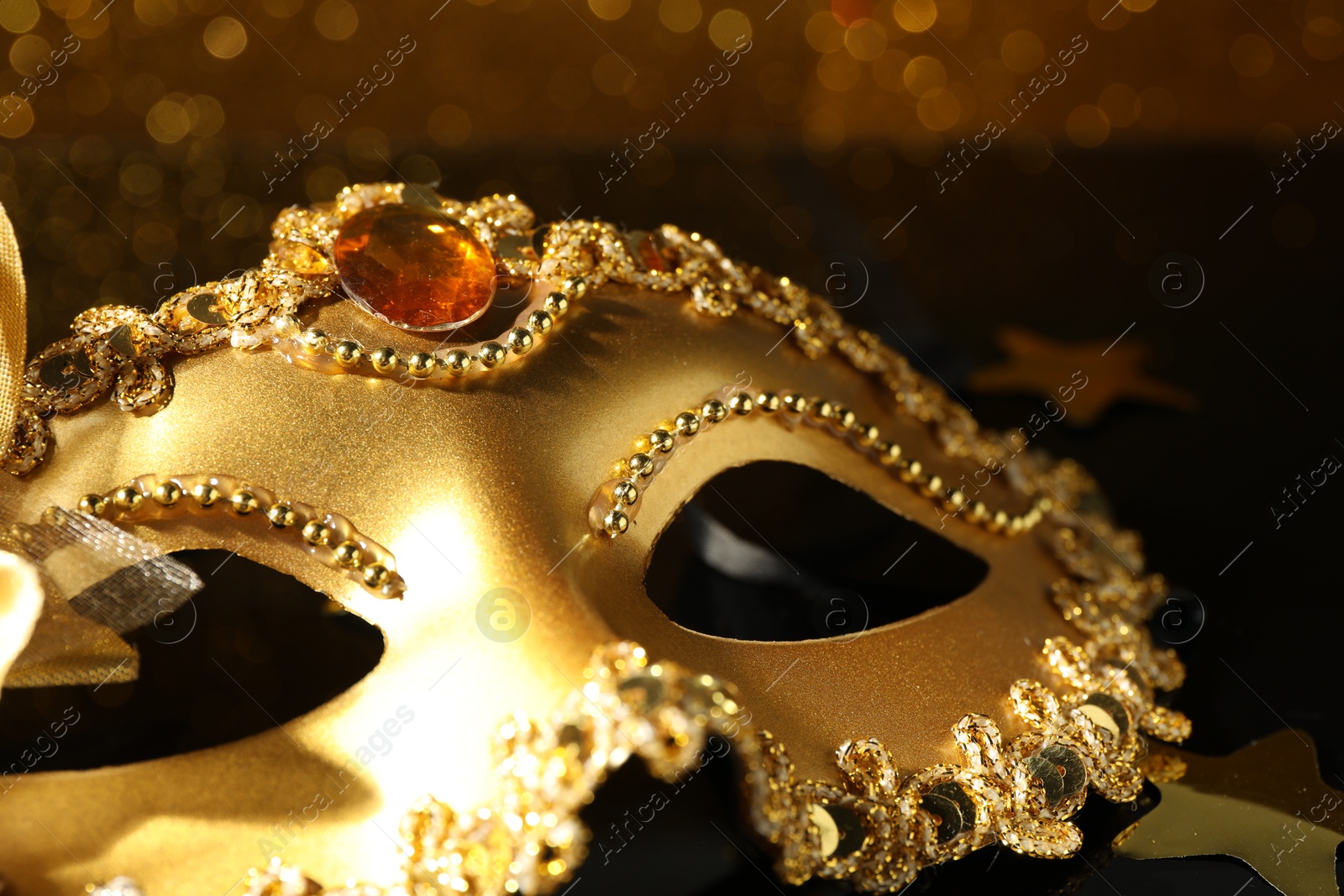 Photo of Beautiful golden carnival mask on table, closeup view