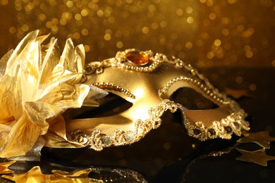 Beautiful golden carnival mask on mirror surface, closeup