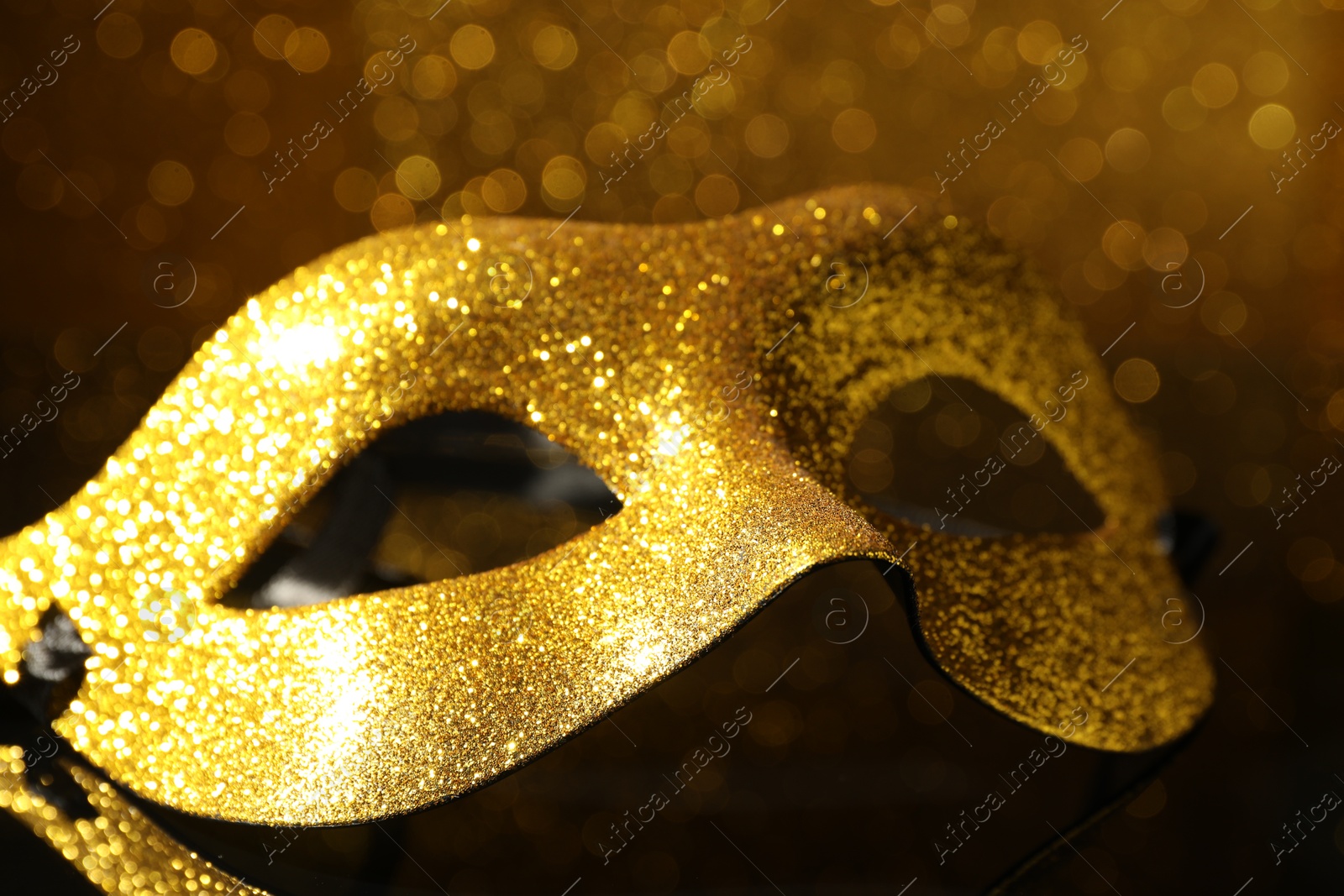 Photo of Beautiful golden carnival mask on mirror surface, closeup