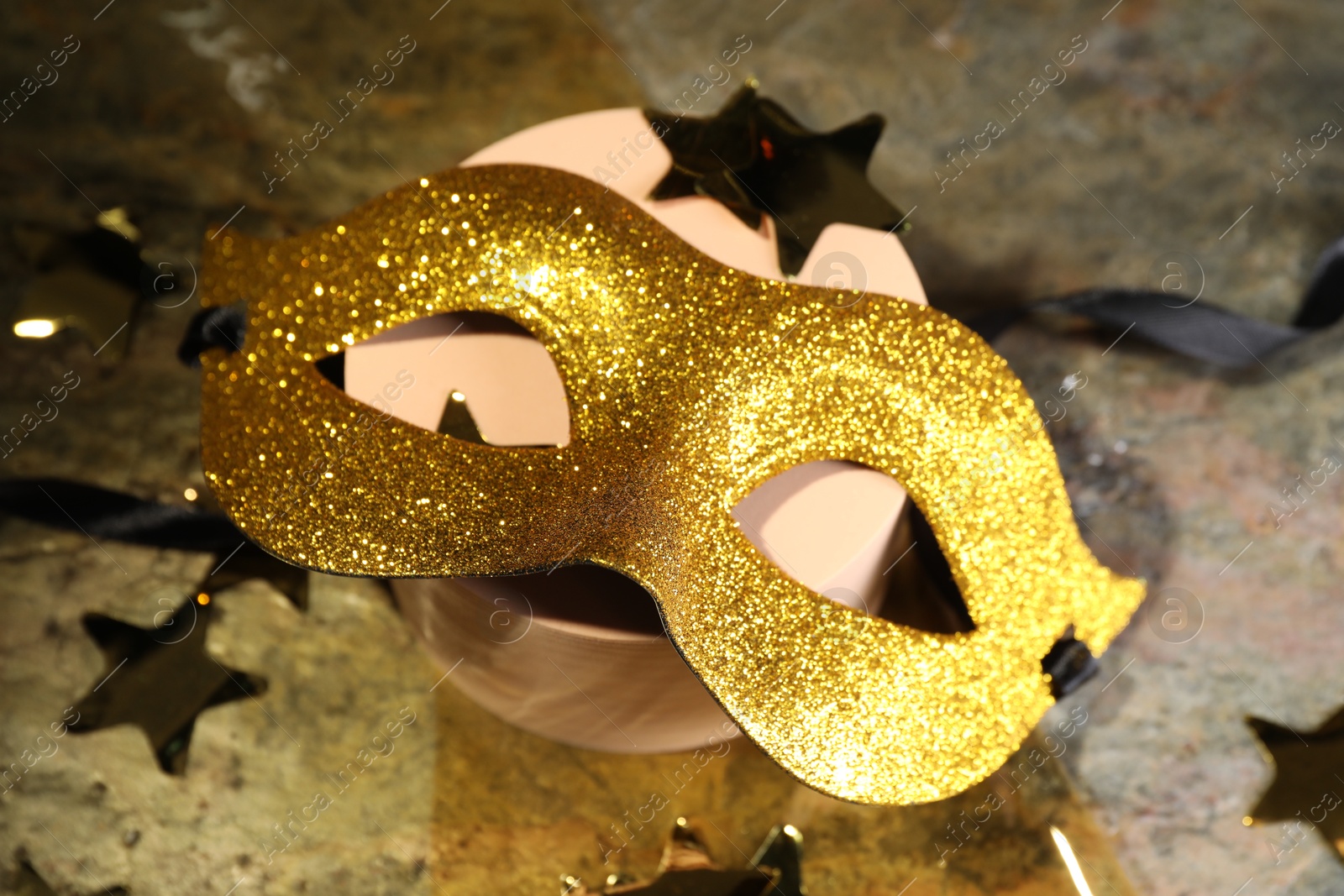 Photo of Beautiful golden carnival mask and decorative stars on table, closeup