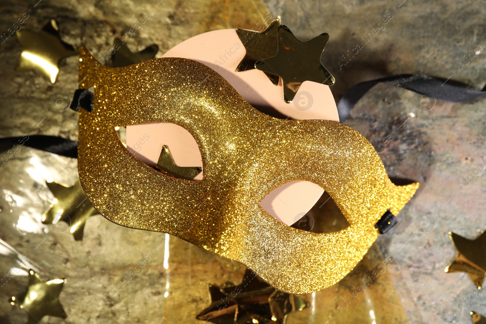 Photo of Beautiful golden carnival mask and decorative stars on table, top view