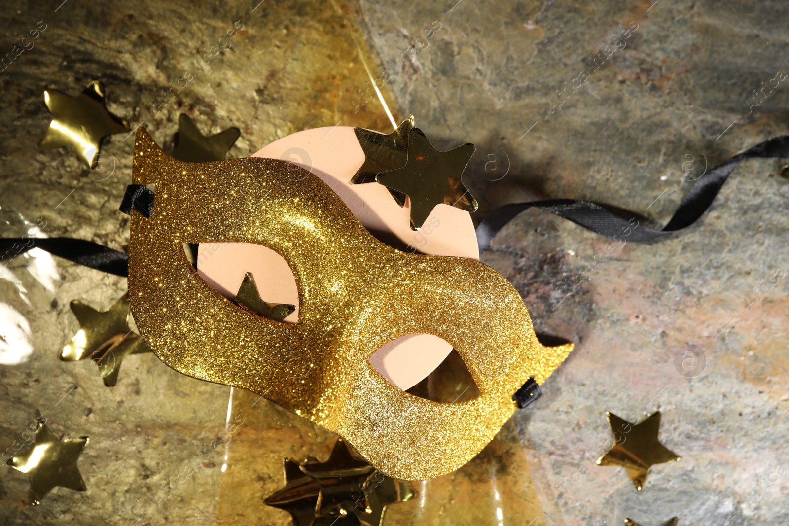 Photo of Beautiful golden carnival mask and decorative stars on table, top view