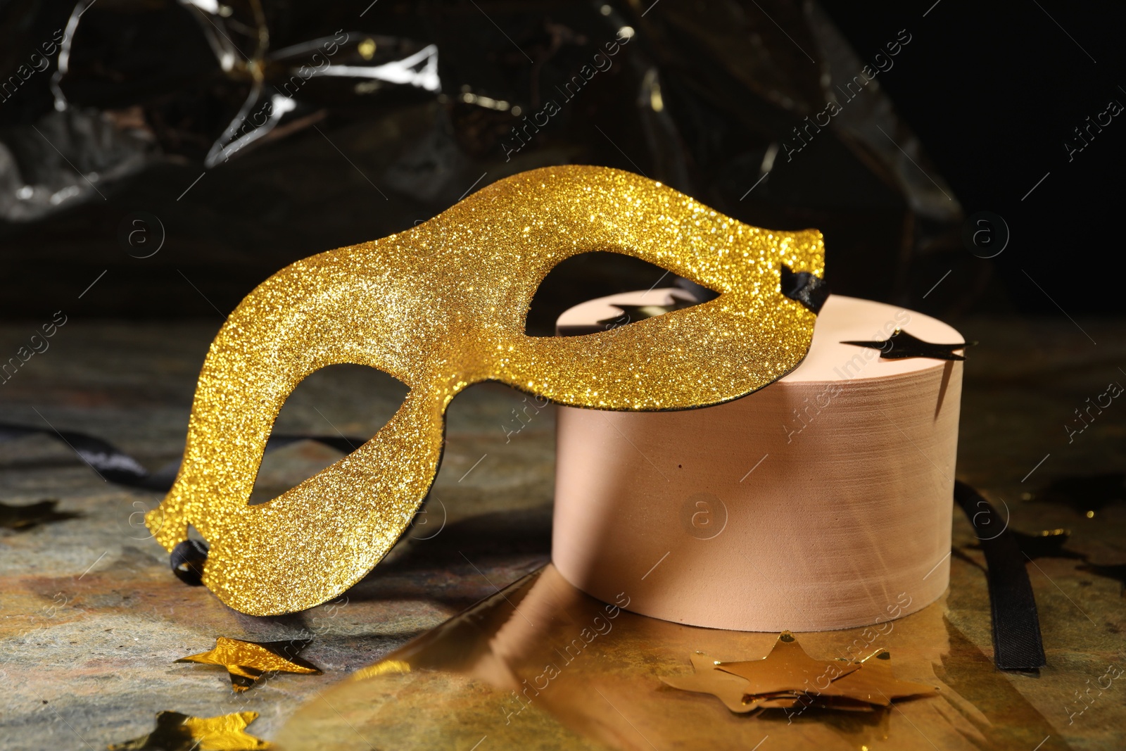 Photo of Beautiful golden carnival mask and decorative stars on grey table