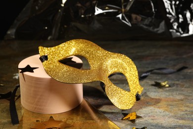 Beautiful golden carnival mask and decorative stars on grey table