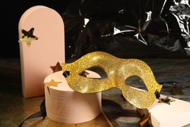 Beautiful golden carnival mask and decorative stars on grey table