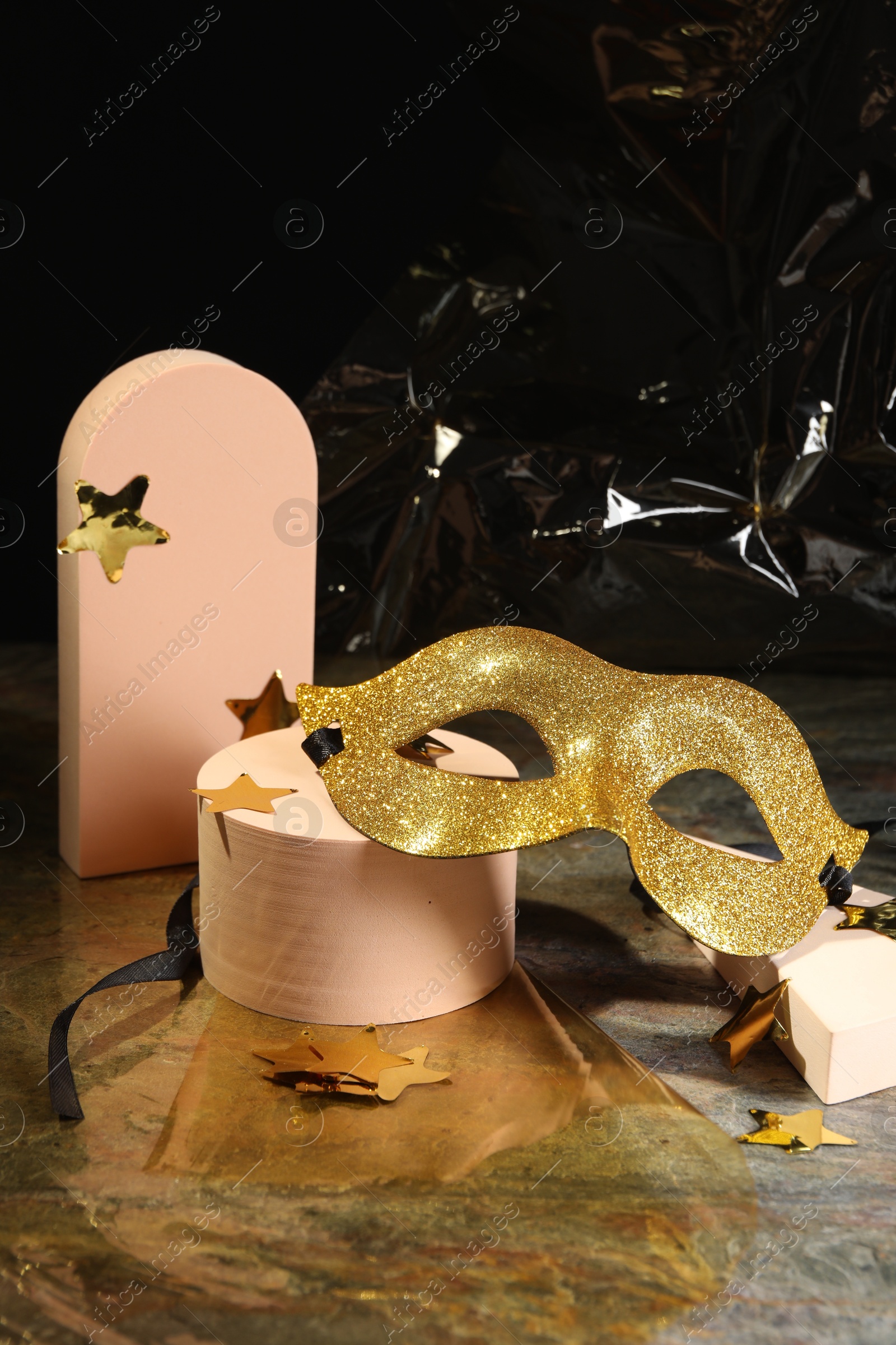 Photo of Beautiful golden carnival mask and decorative stars on grey table