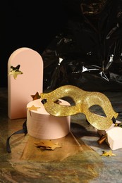 Photo of Beautiful golden carnival mask and decorative stars on grey table