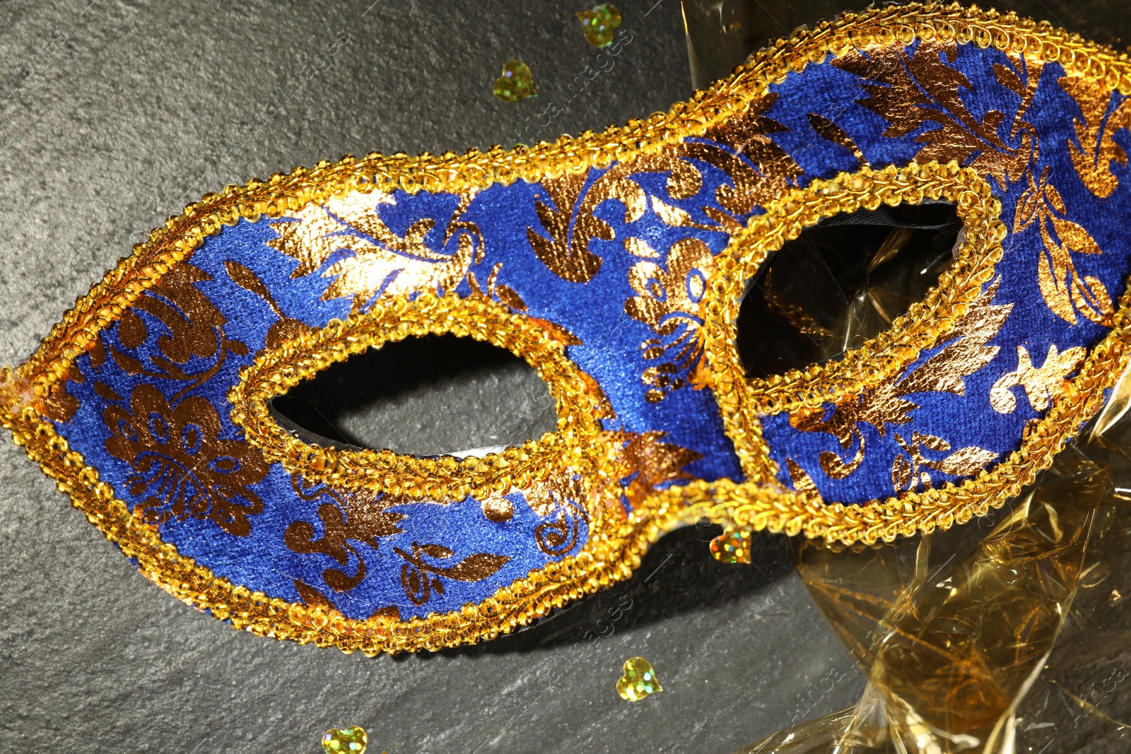 Photo of Beautiful bright carnival mask on grey textured table, top view