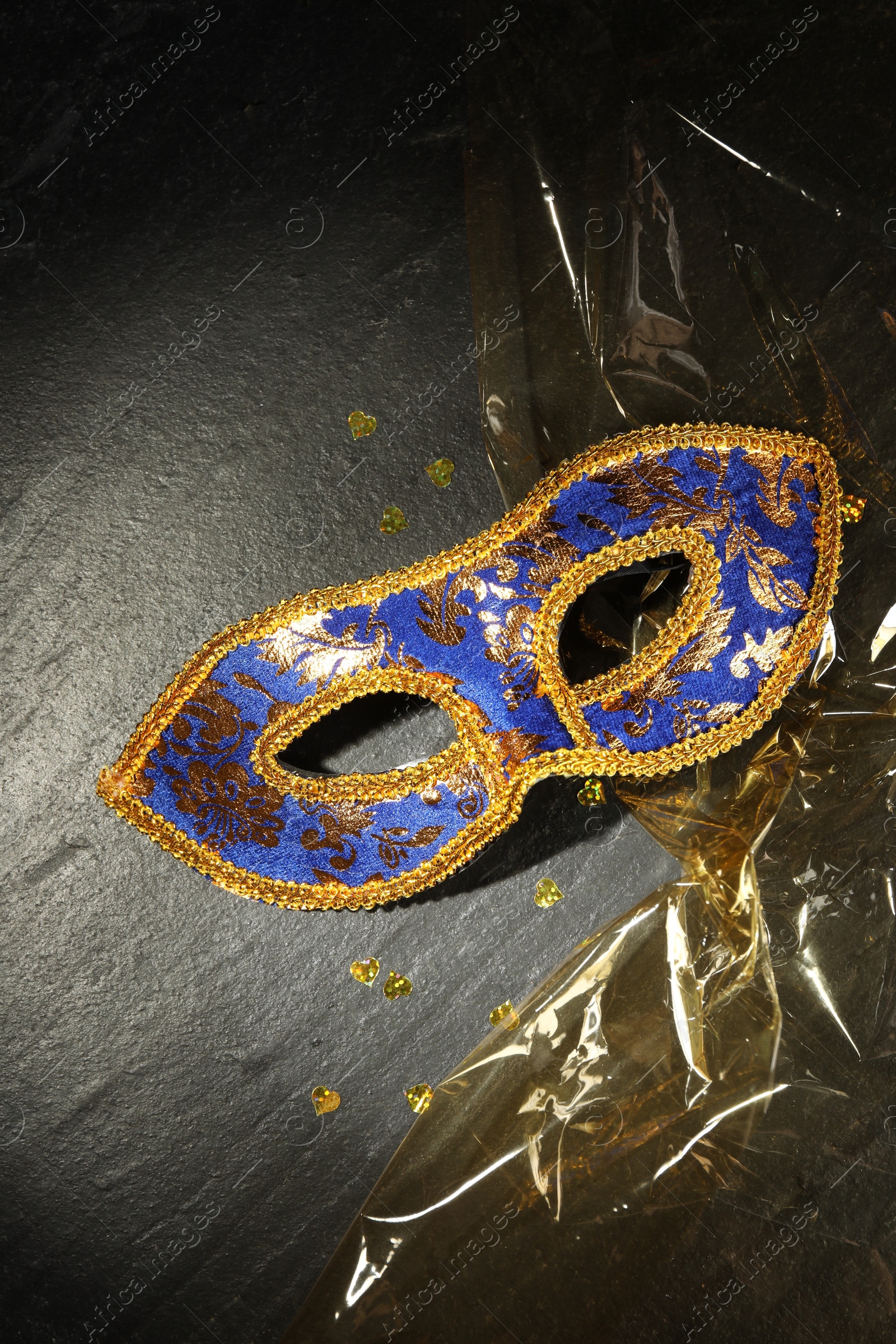 Photo of Beautiful bright carnival mask on grey textured table, top view