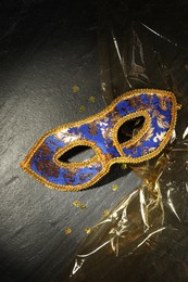 Photo of Beautiful bright carnival mask on grey textured table, top view