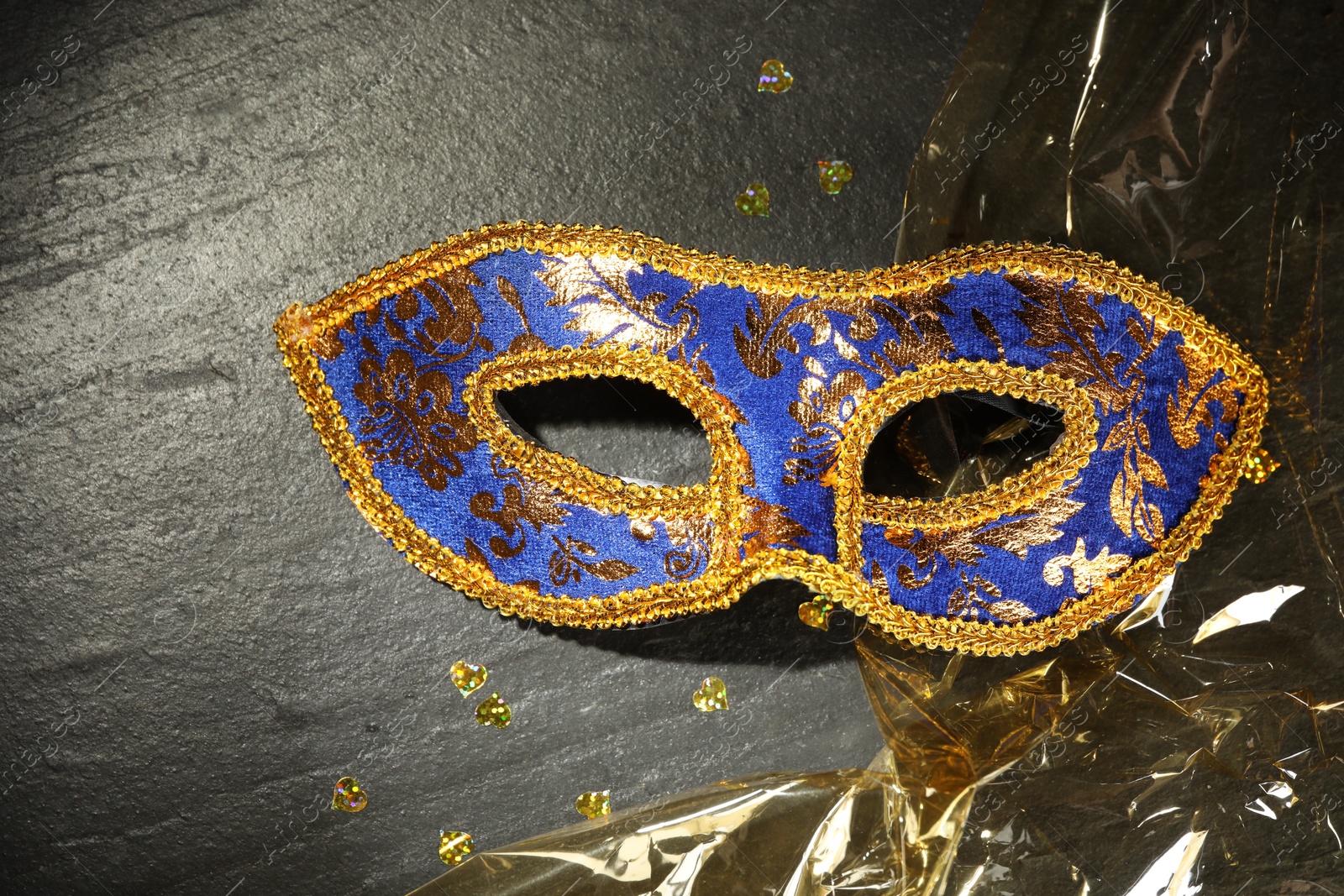 Photo of Beautiful bright carnival mask on grey textured table, top view