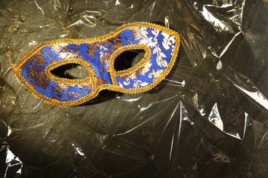 Beautiful bright carnival mask on textured table, top view