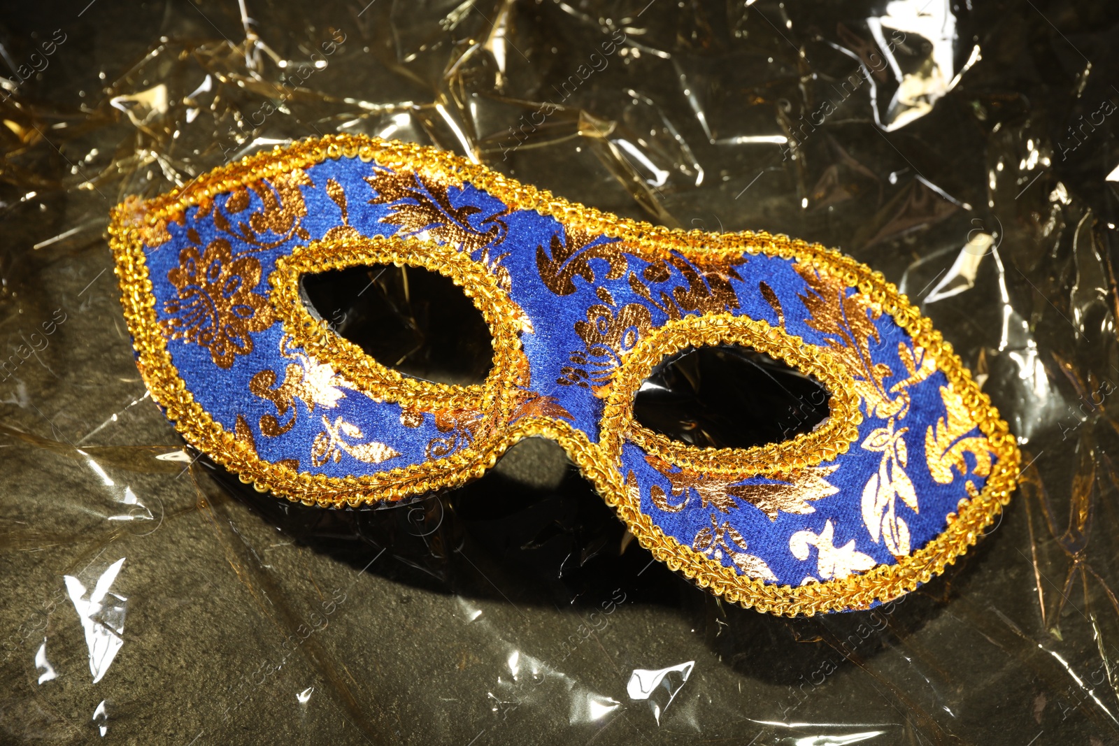 Photo of Beautiful bright carnival mask on textured table, closeup