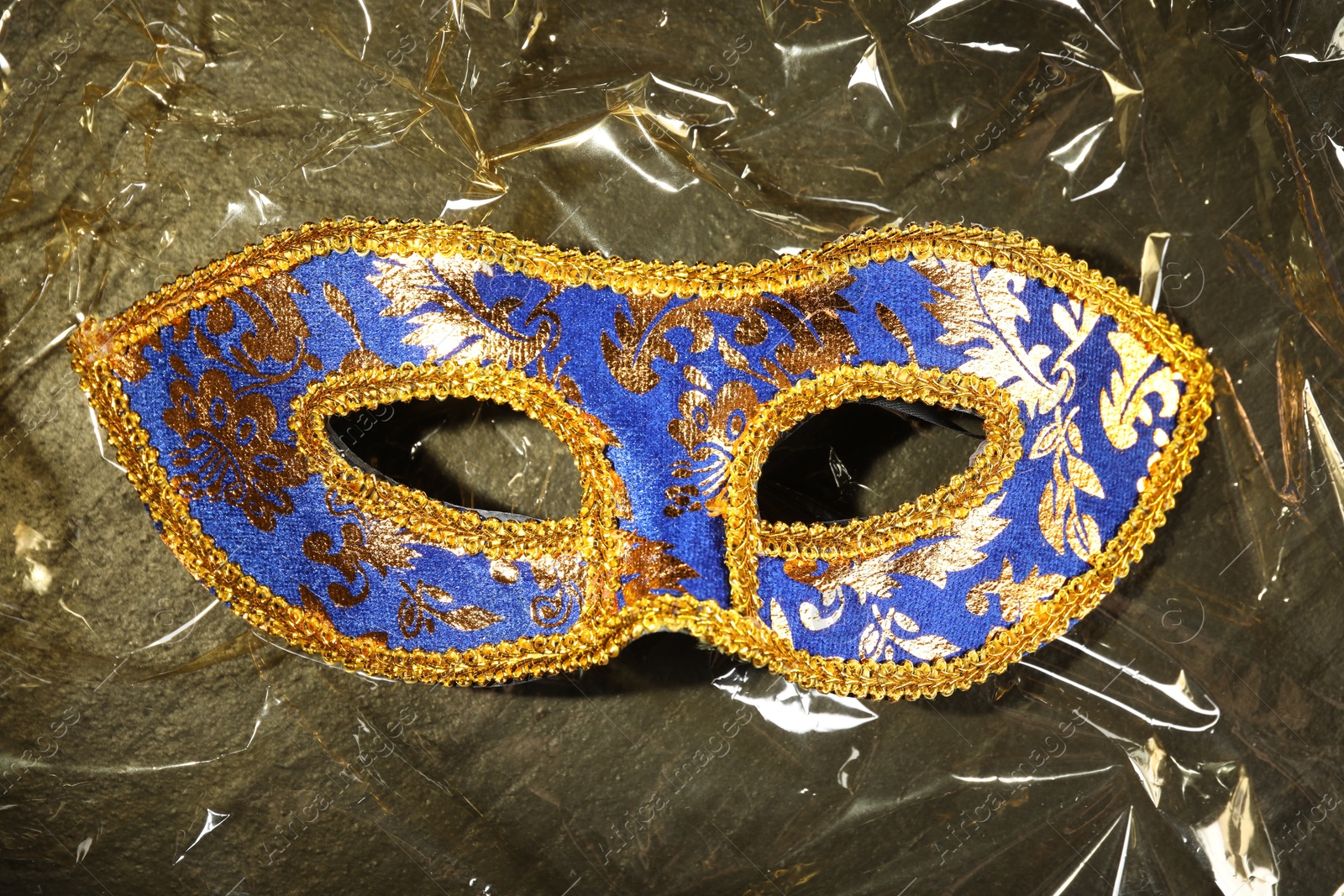 Photo of Beautiful bright carnival mask on textured table, top view