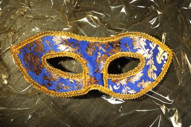 Beautiful bright carnival mask on textured table, top view