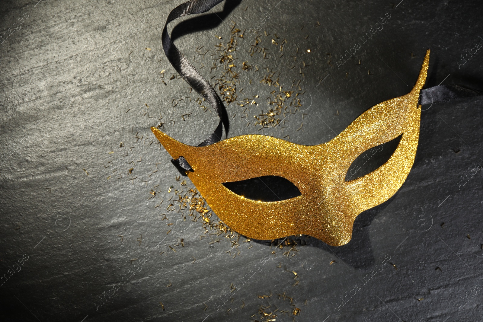 Photo of Beautiful golden carnival mask on grey textured table, top view