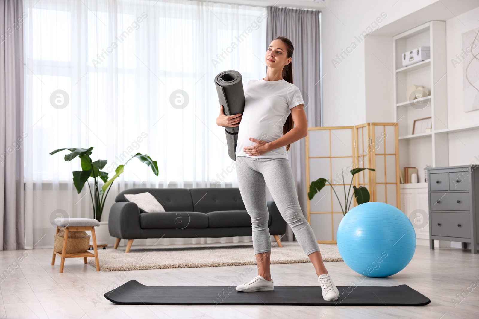 Photo of Pregnant woman with exercise mat and fitball at home