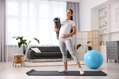 Pregnant woman with exercise mat and fitball at home