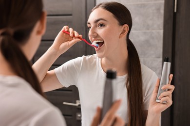 Photo of Beautiful woman brushing her teeth in bathroom