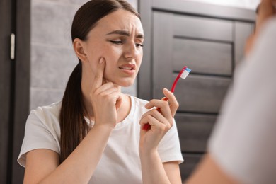 Photo of Young woman with toothbrush suffering from toothache in bathroom