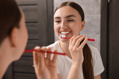 Photo of Beautiful woman brushing her teeth in bathroom