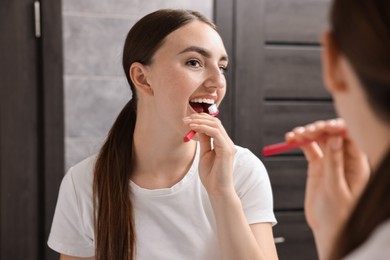 Photo of Beautiful woman brushing her teeth in bathroom