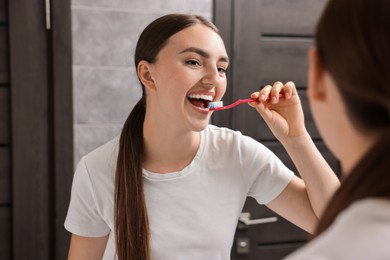 Photo of Beautiful woman brushing her teeth in bathroom