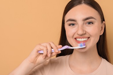 Photo of Beautiful woman brushing her teeth on beige background, space for text