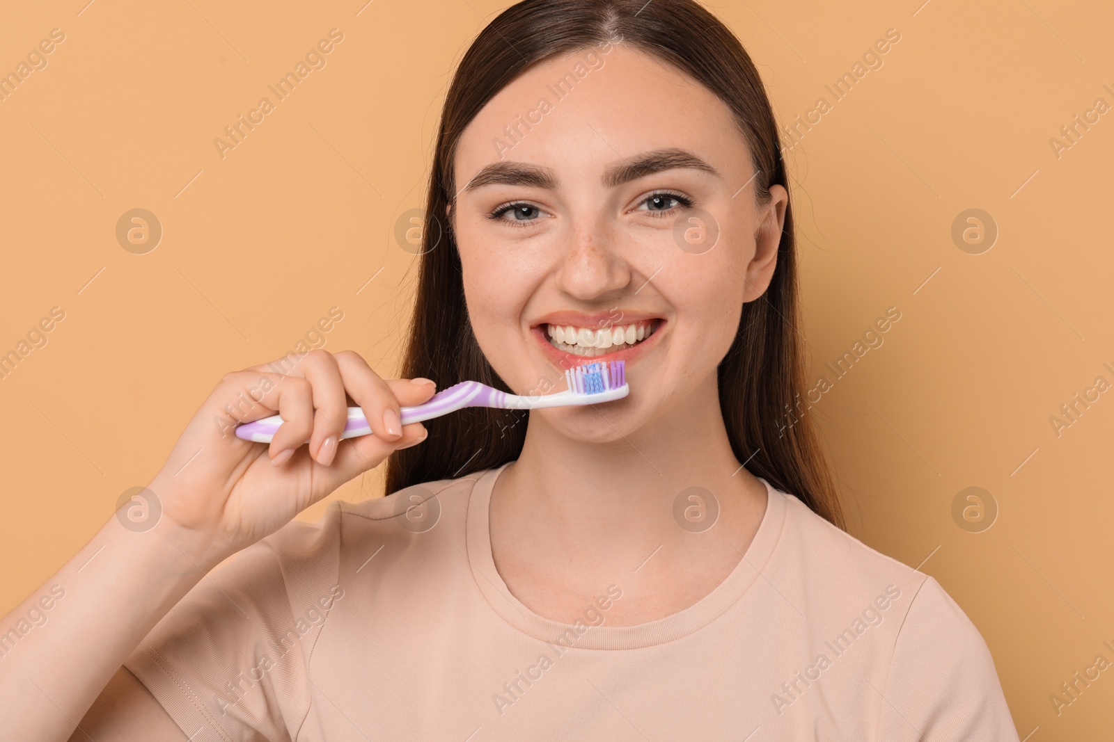 Photo of Beautiful woman brushing her teeth on beige background