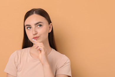 Photo of Beautiful woman brushing her teeth on beige background, space for text