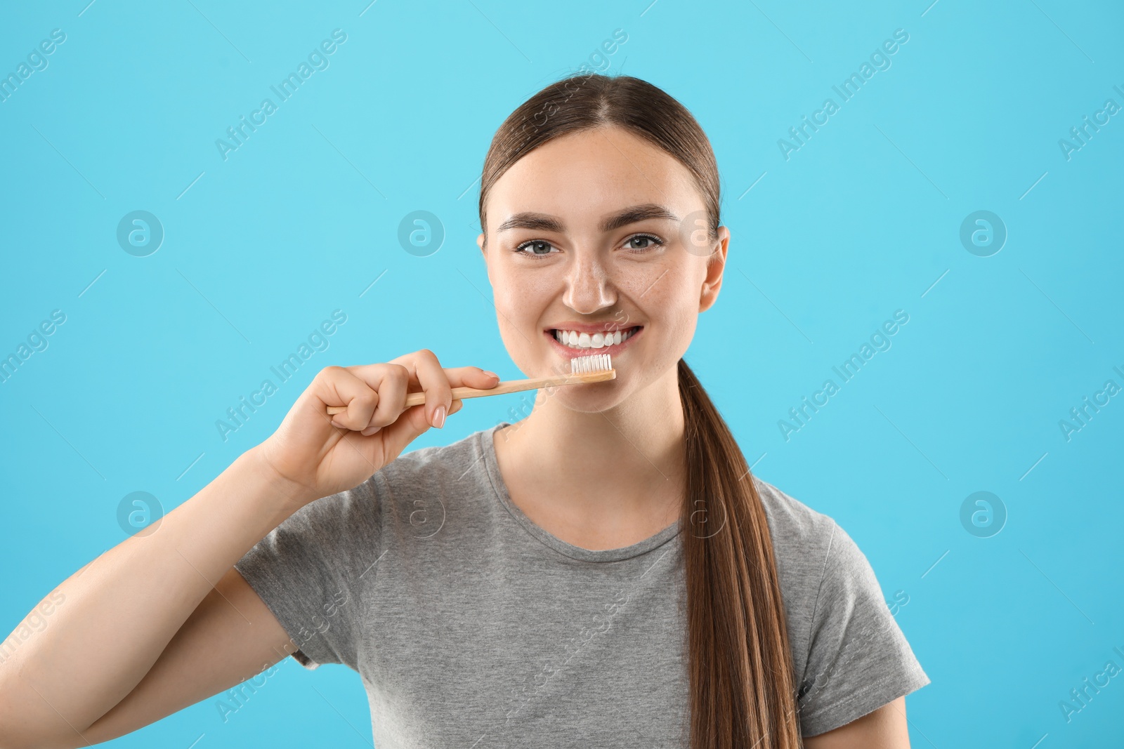 Photo of Beautiful woman brushing her teeth on light blue background