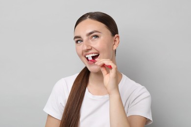 Beautiful woman brushing her teeth on gray background