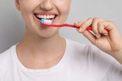 Photo of Woman brushing her teeth on gray background, closeup