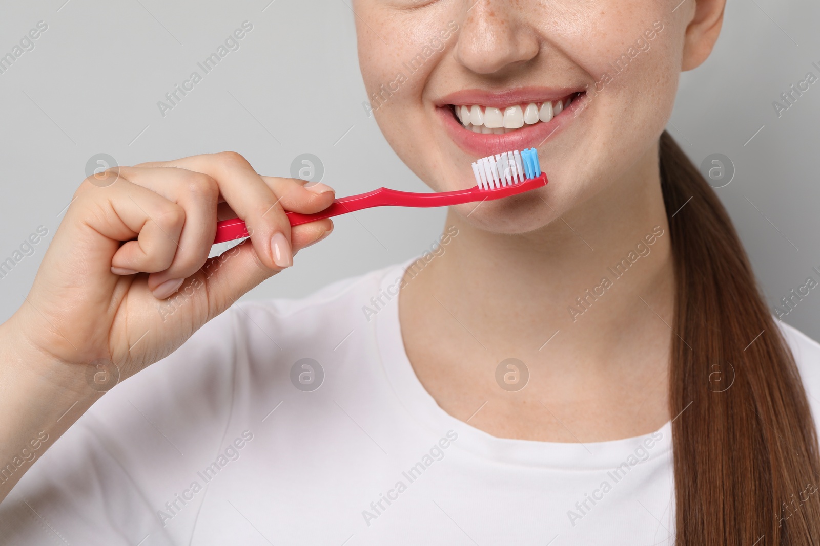 Photo of Woman brushing her teeth on gray background, closeup