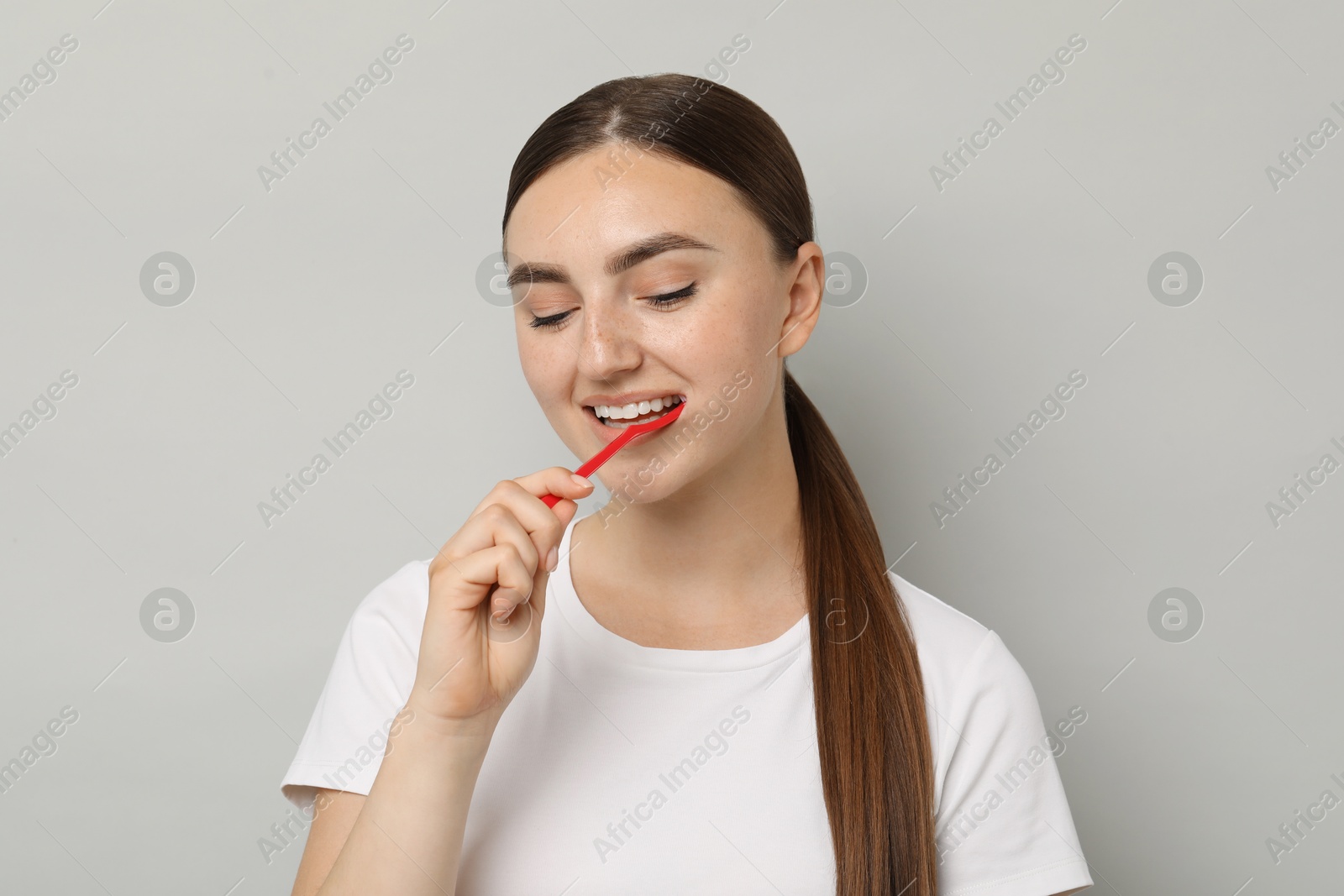 Photo of Beautiful woman brushing her teeth on gray background