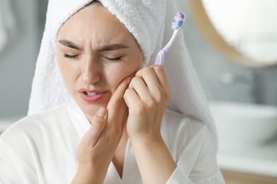 Photo of Young woman with toothbrush suffering from toothache in bathroom