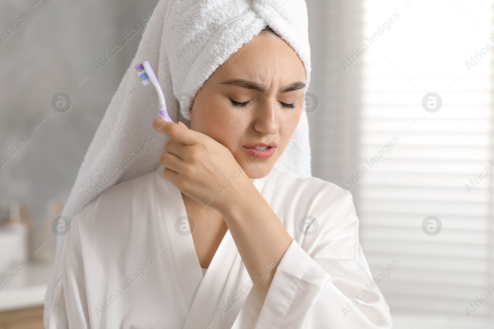 Photo of Young woman with toothbrush suffering from toothache in bathroom