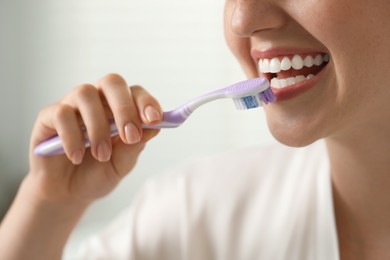 Photo of Woman brushing her teeth in bathroom, closeup