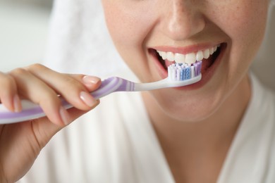 Photo of Woman brushing her teeth in bathroom, closeup