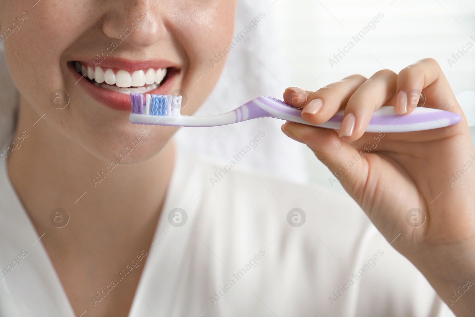 Photo of Woman brushing her teeth in bathroom, closeup