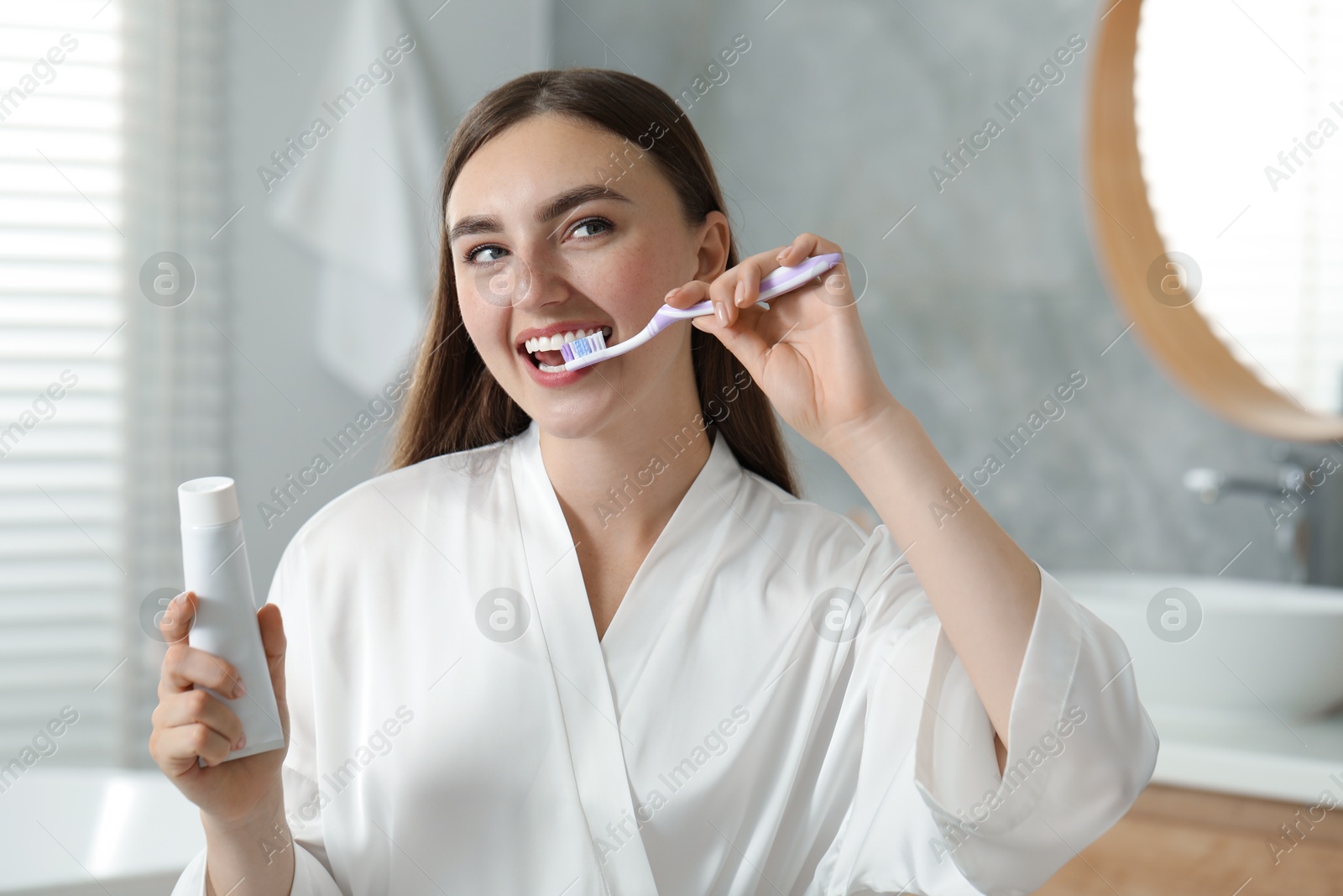 Photo of Beautiful woman brushing her teeth in bathroom