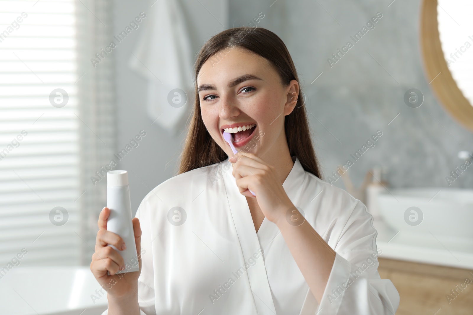 Photo of Beautiful woman brushing her teeth in bathroom