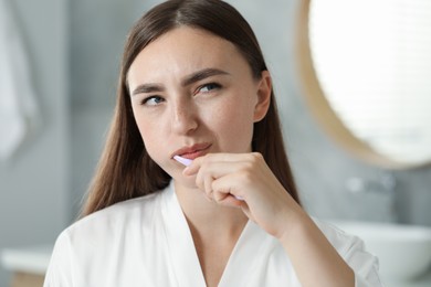 Photo of Beautiful woman brushing her teeth in bathroom