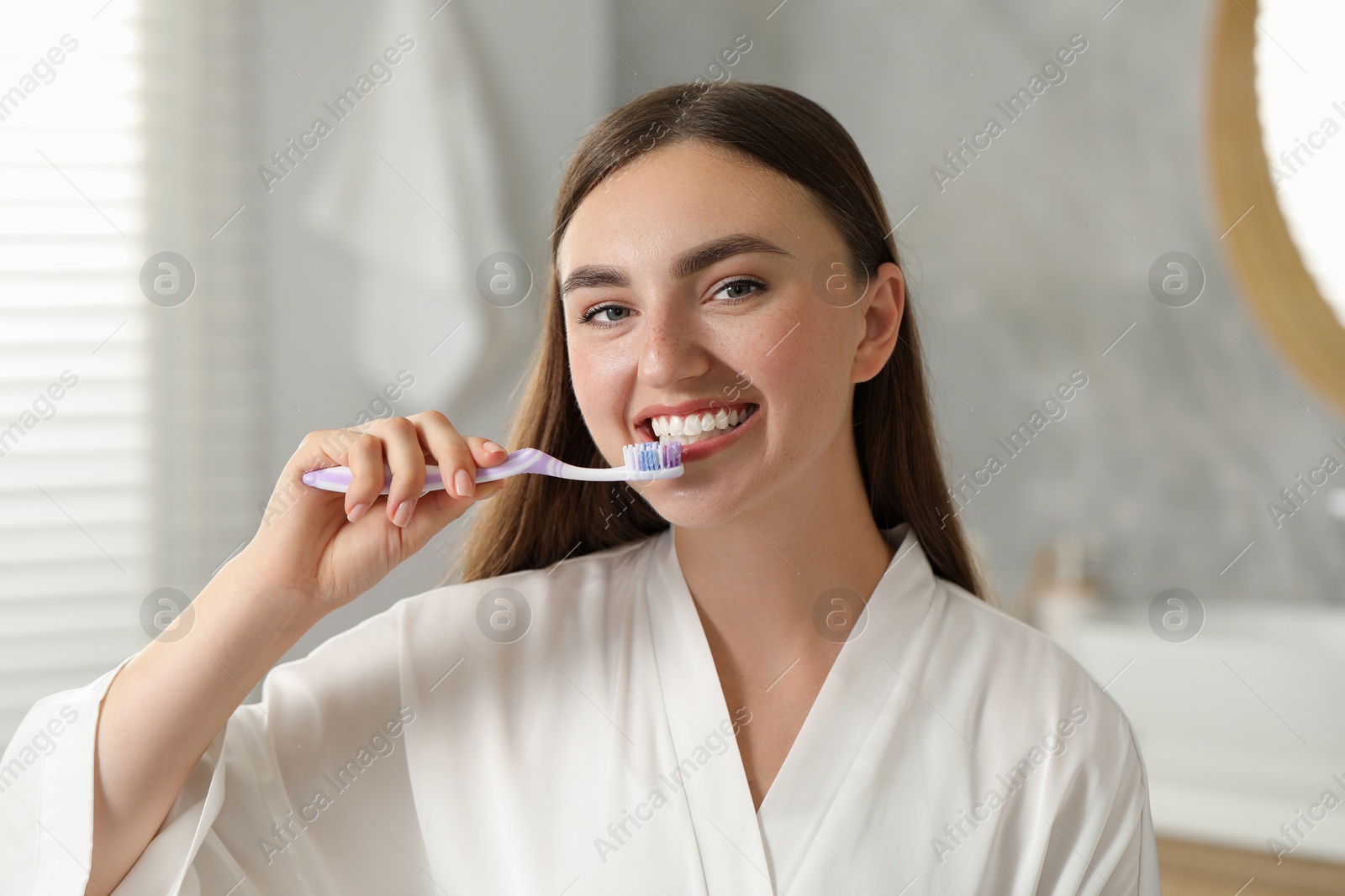 Photo of Beautiful woman brushing her teeth in bathroom