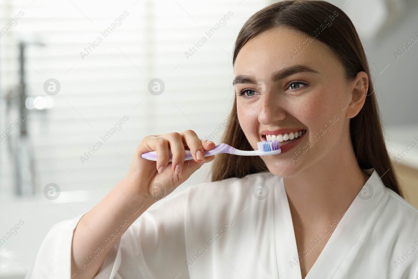 Photo of Beautiful woman brushing her teeth in bathroom